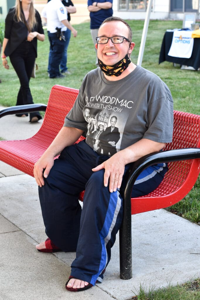 smiling gentleman seated outdoors on a red bench