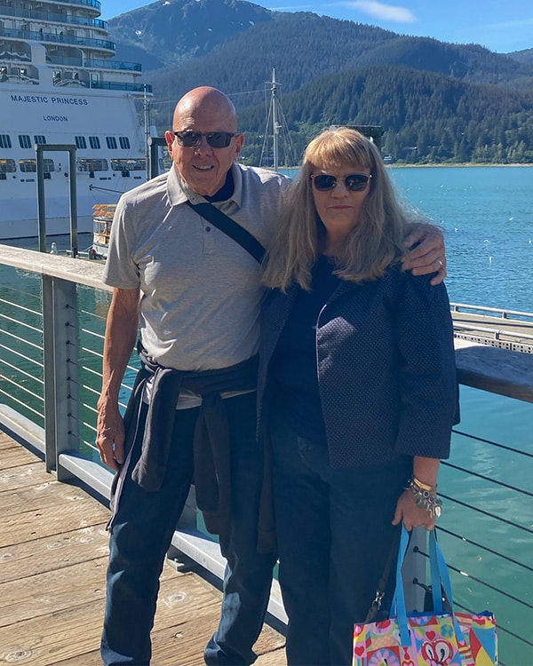 Smiling couple standing on dock in front of Majestic Princess cruise ship
